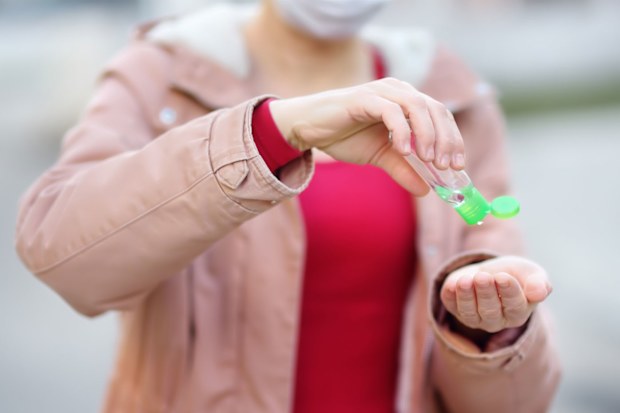 Woman sanitising her hands while wearing a face mask