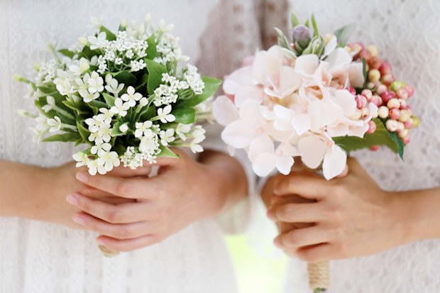 Two women holding wedding bouquets, close up on their hands.
