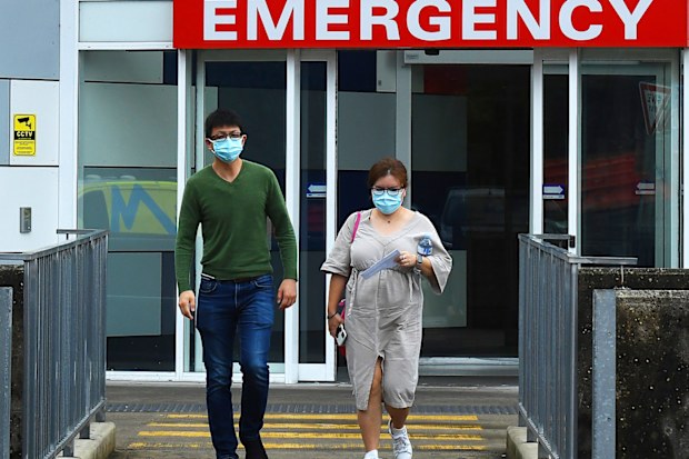 Two people wearing face masks walk out of the emergency entrance at Westmead Hospital, in Sydney's west.