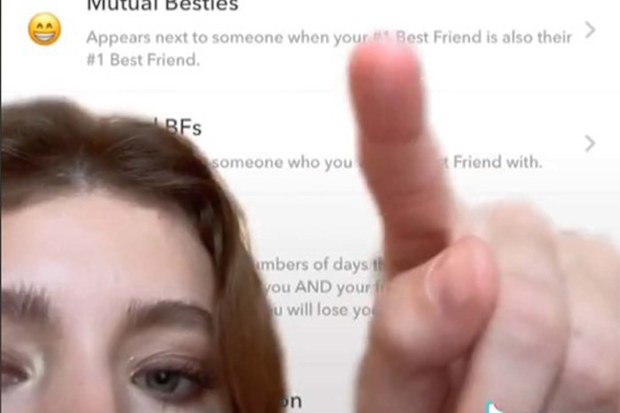 Girl pointing at a greenscreen background of the emoji guide for Snapchat