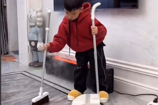Little boy sweeping with a broom.