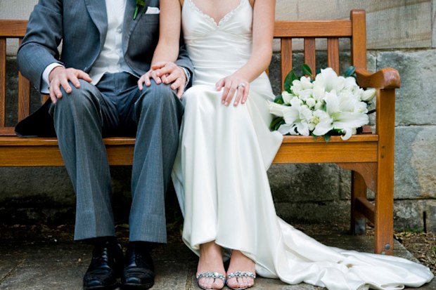Bride and groom sitting on bench.