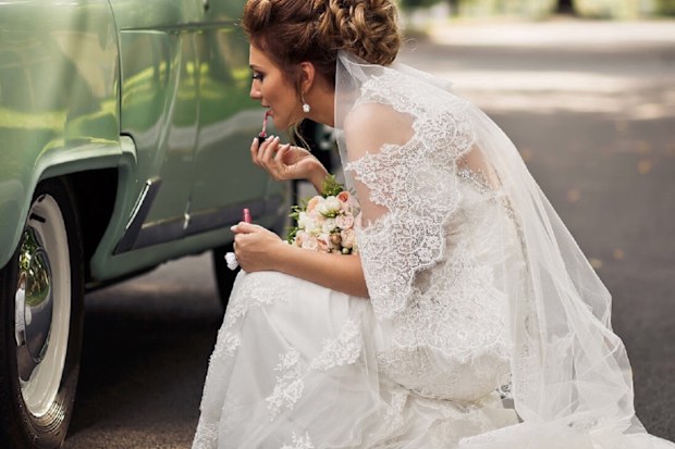 Bride putting on makeup in car reflection