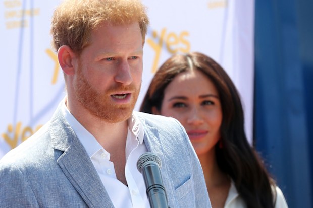 Prince Harry delivers a speech during the royal tour of Africa while wife Meghan Markle looks on.