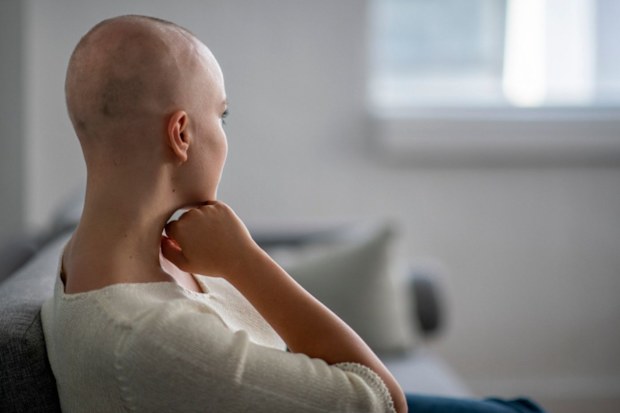 Female cancer patient with back facing camera looking out into the distance.