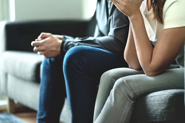 Man and woman sitting on a couch tired from fighting