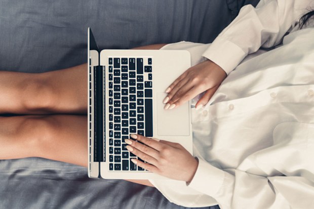 Woman working from home in bed with laptop computer