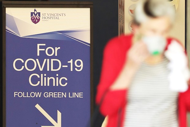 A woman passes a sign for a COVID -19 Clinic as she exits St Vincent's hospital in Sydney, Australia.