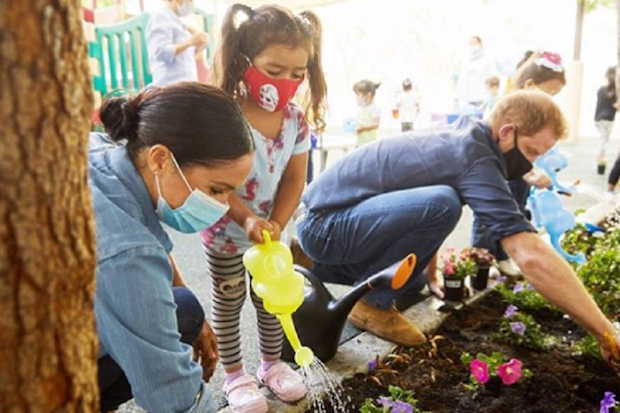 Harry and Meghan planting a garden at a preschool.