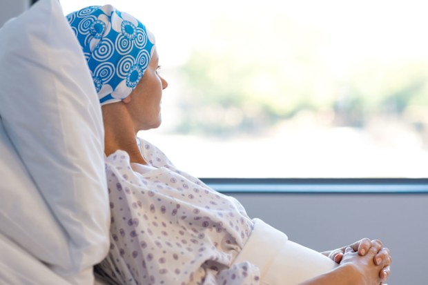 Woman with cancer wearing headscarf in hospital bed