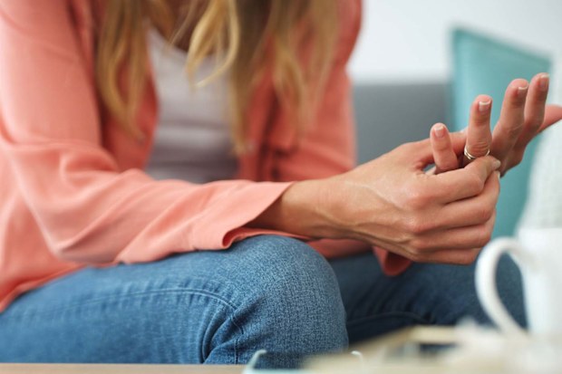 Woman sitting on her couch, playing with her wedding ring and contemplating taking it off