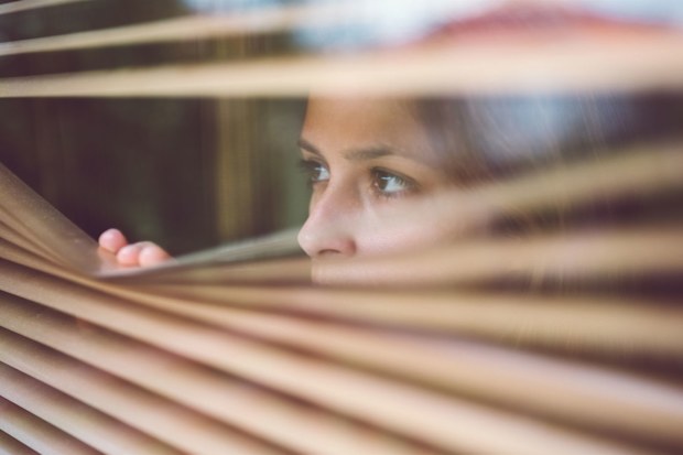 Woman looking through blinds in house