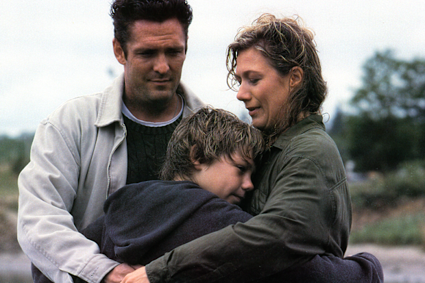 Jason James Richter holding onto Michael Madsen and Jayne Atkinson in a scene from the film Free Willy, 1993. 