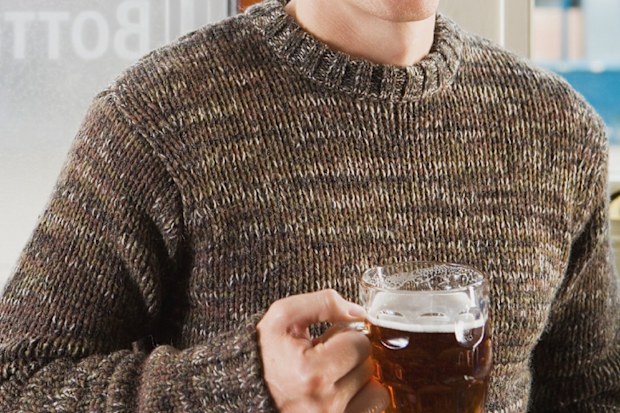 Man wearing jumper drinking beer in pub