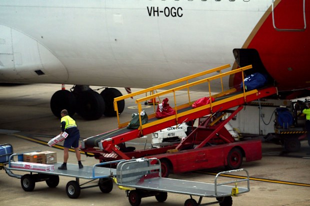 A Qantas baggage handler loads luggage of passengers onto a plane at Sydney Airport