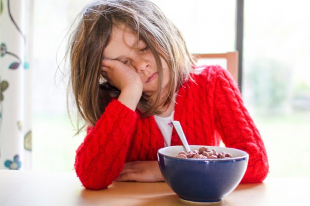 Tired mother, trying to pour coffee in the morning with cereal