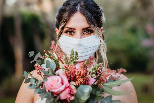 Bride holding flowers and wearing coronavirus mask.