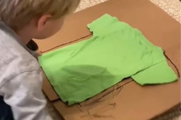 Little kid folding clothes with homemade clothes folder