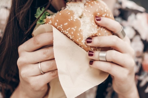 woman eating hamburger with beetroot slices