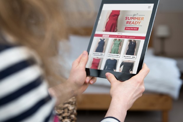 A woman is shopping on a digital tablet on a shopping website on the internet. Screen content is photographer's own design/imagery.