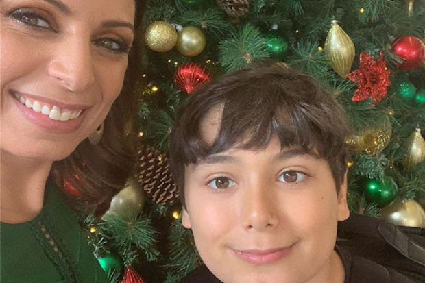 Jo Abi and her son standing in front of a Christmas tree