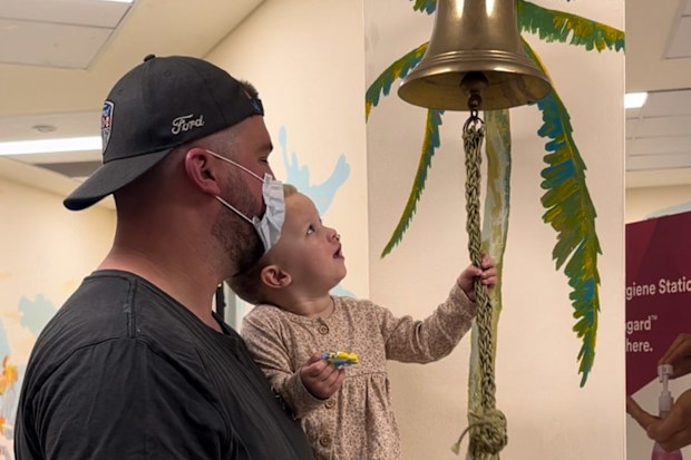 Allegra rings the hospital bell in dad Brandon's arms.