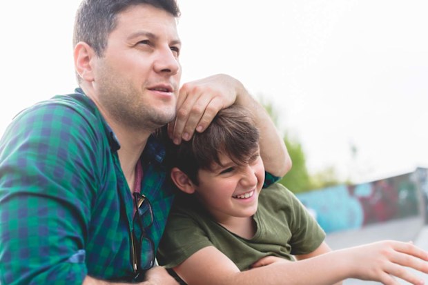 Man hugging boy and messing with his hair as the boy laughs