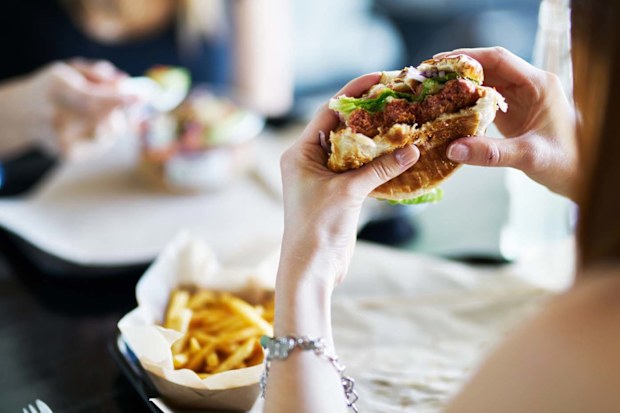 A woman eating a burger in a restaurant.