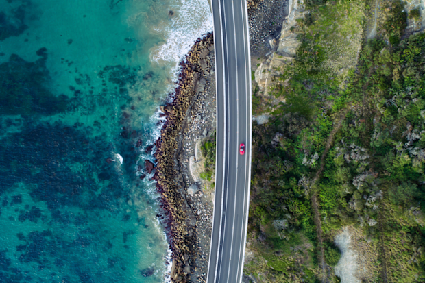 Aerial view of car driving over Sea Cliff Bridge on NSW coast