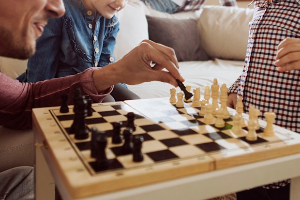 Young family enjoying time at home playing chess together