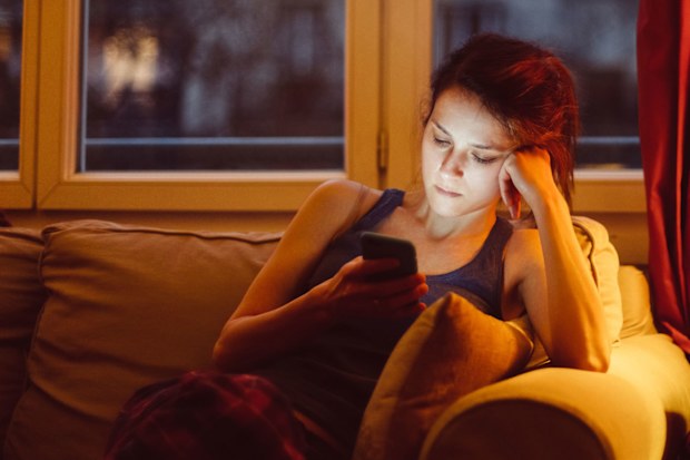 Woman at home alone texting on her phone.