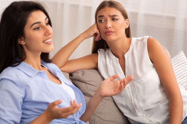 Two women talking, one looking annoyed