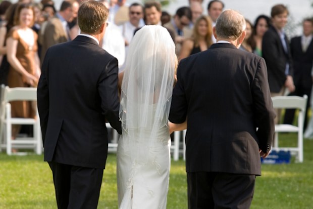 A bride being escorted by her father and grandfather at wedding.