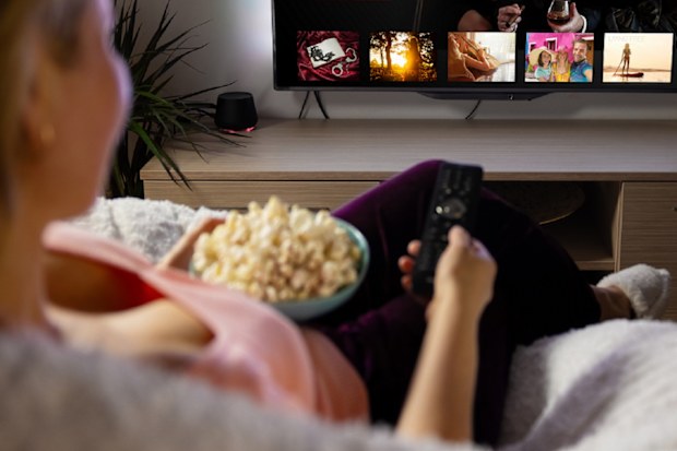 woman watching TV eating popcorn
