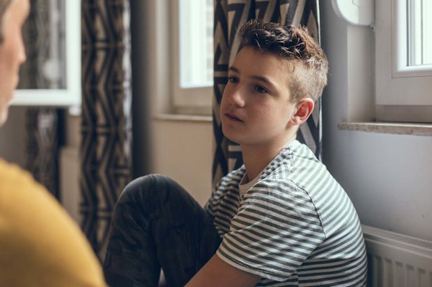 A teenage boy solemnly talking to a male figure