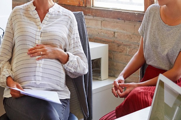 Pregnant woman sitting with colleagues at work