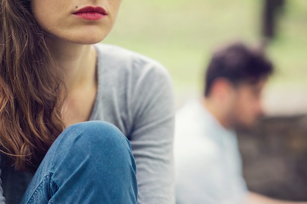 Couple in the park sitting away from each other