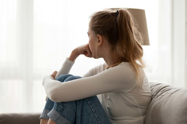 Frustrated woman sitting on the couch looking away from camera