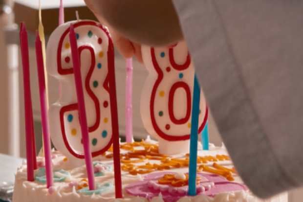 This is 40 movie birthday celebration placing candles on cake ahead of celebration.
