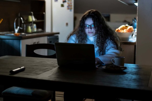 Teenage girl sitting in the dark using the computer