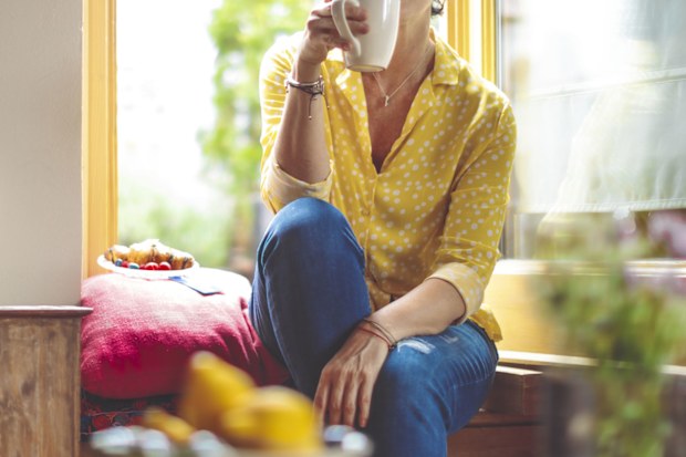 Woman drinking tea at home alone