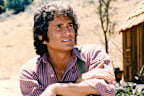 Michael Landon (1936-1991), US actor, poses with his arms crossed and resting on his knee with a log cabin the background in a portrait issued as publicity for the US television series, 'Little House on the Prairie', circa 1974. The drama, adapted from the novels by Laura Ingalls Wilder (1867-1957), starred Landon as 'Charles Ingalls'. (Photo by Silver Screen Collection/Getty Images)