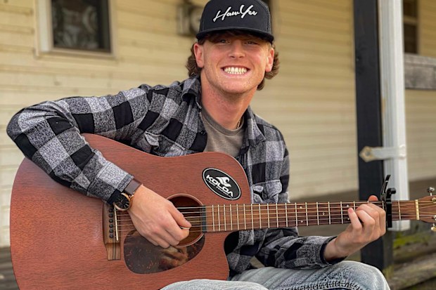 Bailey Zimmerman plays a guitar outside his home in Illinois.