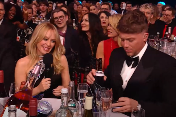 Kylie Minogue and Roman Kemp do a shoey during the 2024 Brit Awards