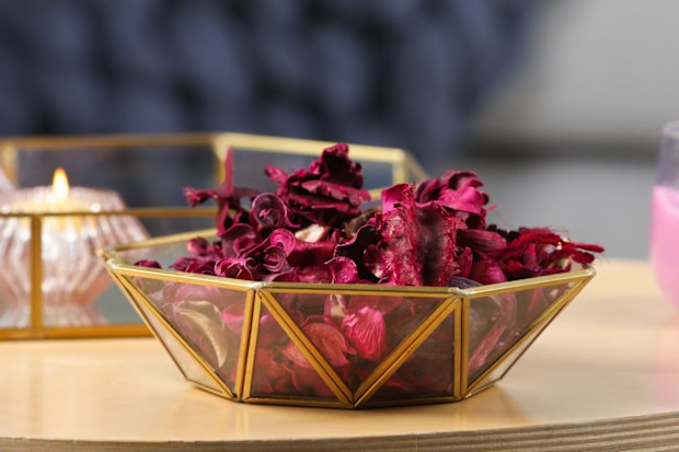 Aromatic potpourri of dried flowers in decorative bowl and burning candles on table indoors, space for text