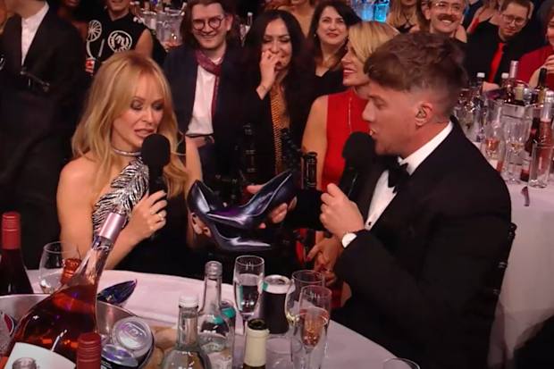 Kylie Minogue and Roman Kemp do a shoey during the 2024 Brit Awards