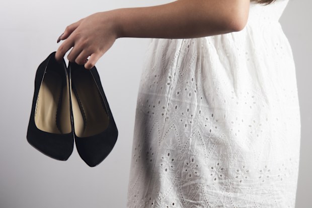 Young woman holding high heels in her hand