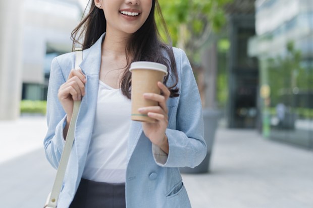 Stock image of a woman walking to her office with a coffee in her hand