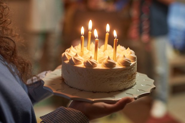 Side view closeup of young woman holding Birthday cake with lit candles at home celebration copy space
