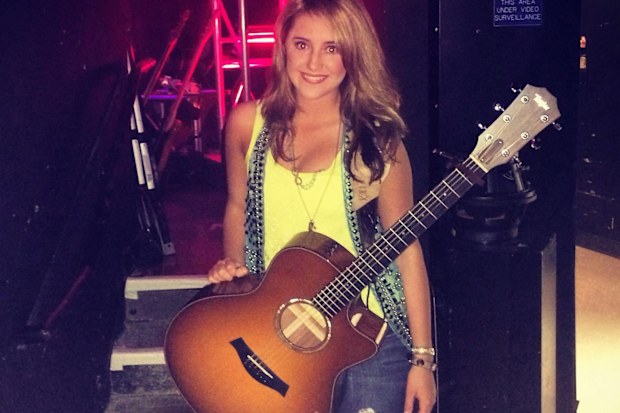 Lainey Wilson poses with her guitar in her 20s.